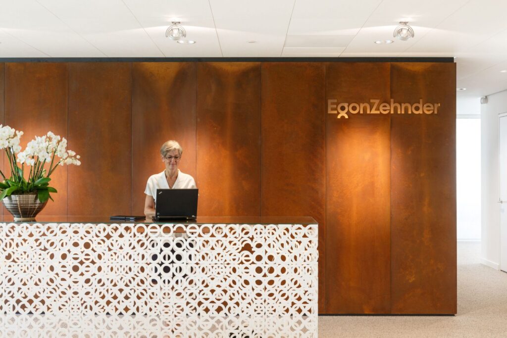 A slender and transparent reception desk conveys the company identity of the global leadership advisory firm Egon Zehnder in Amsterdam. People make the organisation.